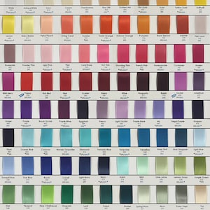 Op de afbeelding: Een kleurenkaart met satijnen lintstalen. De kaart bevat een breed scala aan kleuren, waaronder wit, zwart, rood, blauw, groen, geel, oranje, roze, paars en bruin. Elk kleurenstaal is voorzien van een kleurnaam en een nummer.