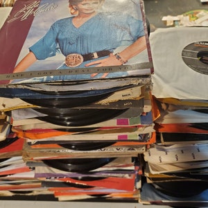 Könnte beinhalten: Ein Stapel Vintage-Schallplatten mit verschiedenen Albumcovern, darunter eines mit einer Frau mit blonden Haaren und einem blauen Hemd. Die Albumcover sind in verschiedenen Farben und haben Text darauf, darunter "MCA" und "Have I Got A Deal For You".