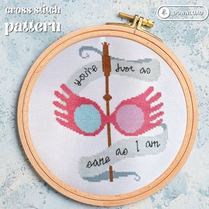May include: Cross stitch pattern featuring a pair of pink glasses with blue lenses, a wand, and the text "You're just as sane as I am".