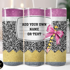 May include: A tumbler with a pencil design. The top is a glittery pink, with a white band, and a black and white speckled pattern. The bottom is gold glitter, with a gray base. The text "ADD YOUR OWN NAME OR TEXT" is on the tumbler, along with a pink bow.