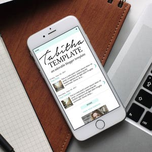 Puede incluir: Un tel&eacute;fono inteligente blanco que muestra una plantilla de sitio web llamada "Tabitha Template" con el texto "una plantilla de blog adorable". La plantilla de sitio web tiene un fondo azul claro con texto blanco e im&aacute;genes. La plantilla de sitio web tiene un bot&oacute;n de inicio y un bot&oacute;n de ver sitio web.
