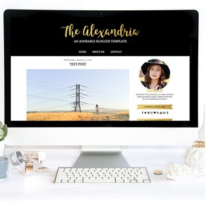 Puede incluir: Una pantalla de ordenador muestra una plantilla de sitio web llamada "The Alexandria" en negro y dorado. La pantalla muestra una entrada de blog con una foto de una mujer y un paisaje. Un teclado y accesorios de escritorio est&aacute;n en primer plano.