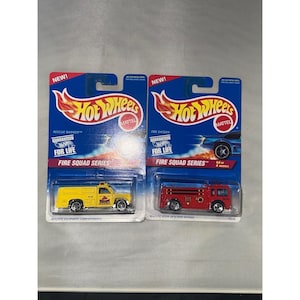 May include: Two Hot Wheels die-cast toy vehicles in original blue blister packaging. The left package contains a yellow Rescue Ranger truck, and the right package contains a red Fire Eater fire engine, both from the Fire Squad Series.