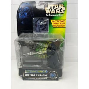 May include: A Star Wars Emperor Palpatine action figure in a clear plastic package. The figure is black and has a hooded robe. The packaging includes the text "ELECTRONIC ENERGY BOLTS REALLY LIGHT UP!"