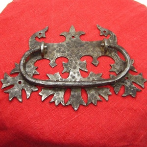 Pode incluir: Uma maçaneta de porta de metal decorativa com um design floral detalhado. A maçaneta é feita de ferro e tem um acabamento escuro e envelhecido.