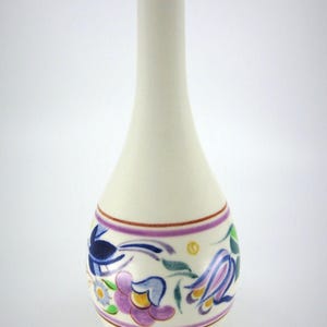 Könnte beinhalten: Eine hohe, schlanke Keramikvase mit cremefarbener Basis. Der Hals ist mit horizontalen blauen und gelben Bändern verziert. Der bauchige Körper zeigt ein handgemaltes Blumenmuster in Violett, Blau, Grün und Gelb, eingerahmt von dünnen violetten Linien.