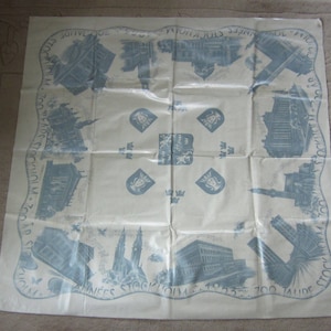 May include: A white tablecloth with a blue and white design featuring images of buildings and the text "700 TALIDE ANNÉES STOCKHOLM 1923 - 1923".