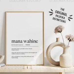 May include: A framed print with a white background and black text. The text reads "mana wahine" and defines the word as "powerful woman, powerful women, female empowerment". The print is on a wooden shelf with two ceramic vases and dried pampas grass.