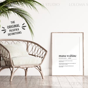 May include: A framed print with the text "mana wahine" and a definition of the word in English. The print is hanging on a white wall in a room with a wicker chair and a potted plant.