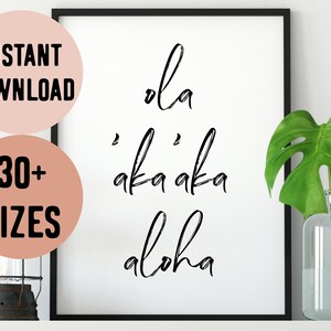 May include: A black and white printable wall art print with the text "ola 'aka 'aka aloha" in a cursive font. The print is framed in a black frame and is displayed on a white wall.