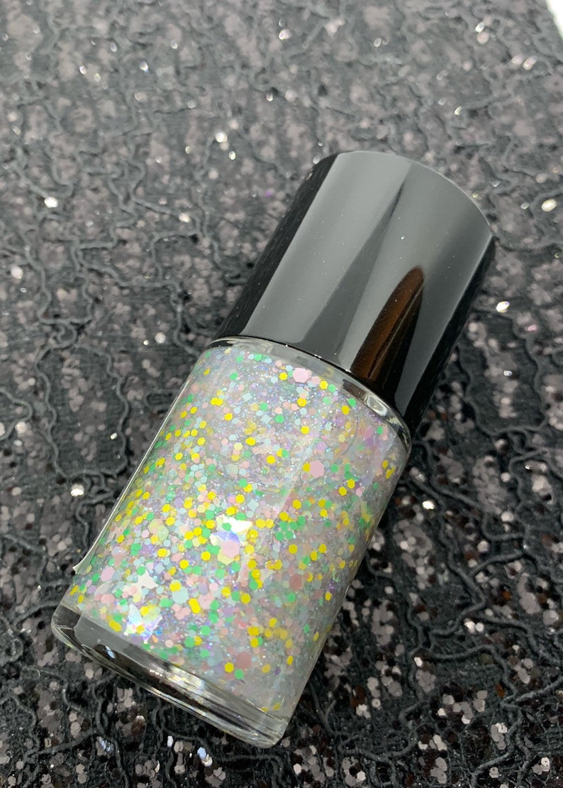 May include: A clear glass bottle of nail polish with a black cap. The polish is a light iridescent color with multi-colored glitter.