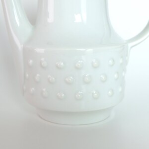 May include: White ceramic teapot with a textured, dotted design around the body.