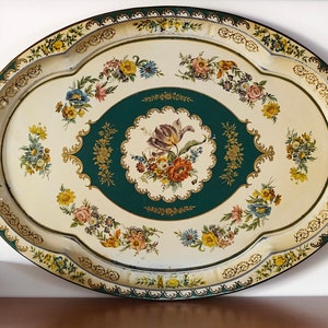 Puede incluir: Una bandeja ovalada para servir con fondo blanco y centro verde. La bandeja está decorada con ribetes dorados y diseños florales.