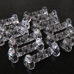 May include: A collection of clear glass bone-shaped decorative pieces with intricate designs. The pieces are arranged in a staggered pattern, creating a visually appealing display.