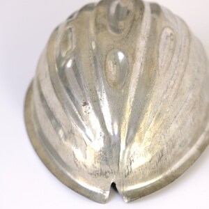 K&ouml;nnte beinhalten: Eine silberne Metallform zum Herstellen einer Gelee oder eines Desserts in Form einer Halbkugel mit geriffeltem Design.