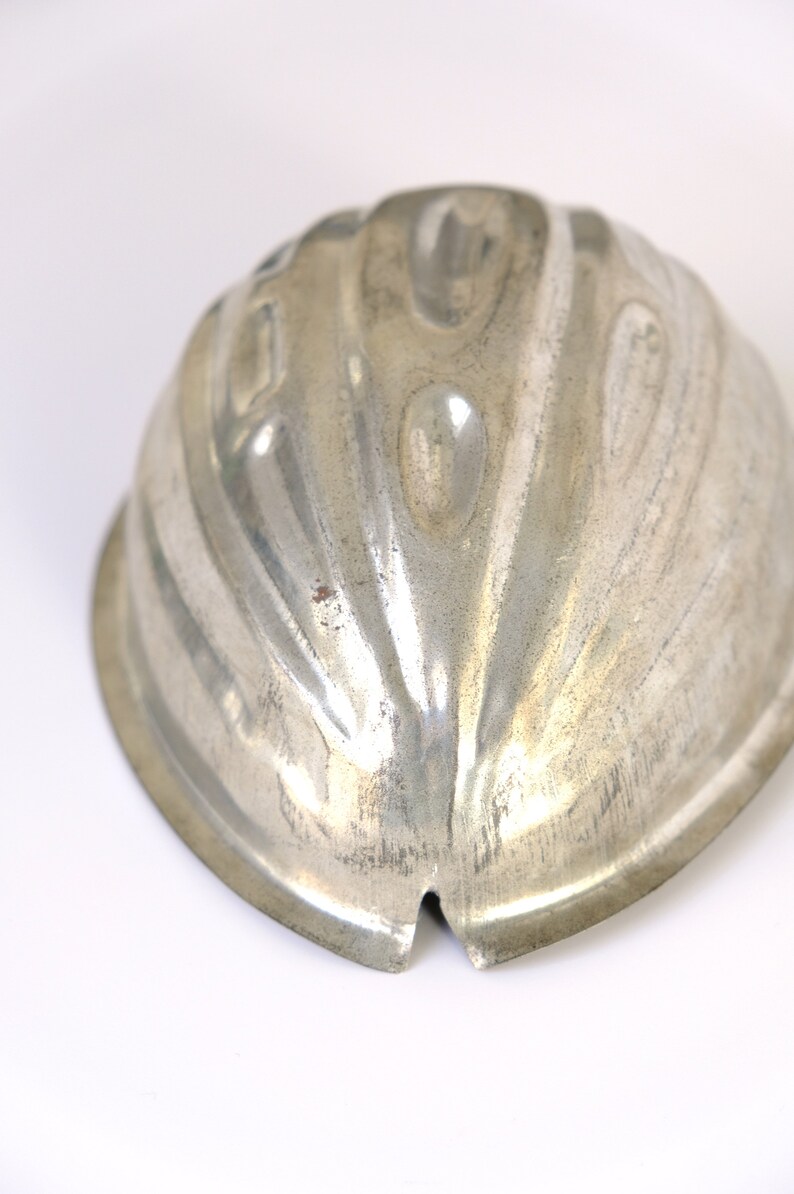 K&ouml;nnte beinhalten: Eine silberne Metallform zum Herstellen einer Gelee oder eines Desserts in Form einer Halbkugel mit geriffeltem Design.