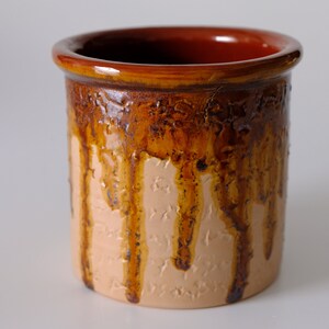 Könnte beinhalten: Eine braune Keramikvase mit einem Tropf-Glazureffekt. Die Vase hat einen hellbraunen Boden mit einer dunkleren braunen Glasur, die an den Seiten heruntertropft.