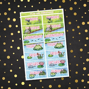 May include: A set of 7 colourful planner stickers featuring days of the week with frog and dragonfly illustrations. The stickers are designed with a pond theme and have a blue, green, and pink colour scheme.