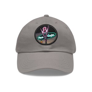 May include: A gray baseball cap with a black and white patch featuring a neon sign that reads "The 8th Cafe".