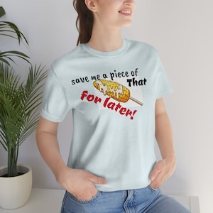 May include: A light blue t-shirt with the text "save me a piece of that for later!" and a cartoon image of a corn on the cob with white sauce.