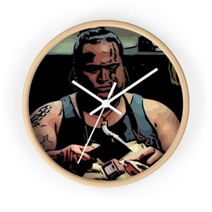 Puede incluir: Un reloj con una ilustración de dibujos animados de un hombre con una expresión seria. Lleva un tanque azul y tiene tatuajes en los brazos. La esfera del reloj es blanca con manecillas negras.