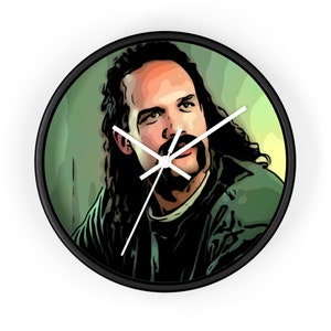 May include: A black and white clock with a cartoon image of a man with long hair and a mustache. The man is wearing a green shirt and has a serious expression on his face.