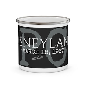May include: White enamel camping mug with a black background and grey text that reads "Disneyland - March 18, 1967 - of the"