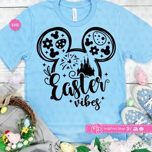May include: Light blue t-shirt with a black Mickey Mouse silhouette design. The silhouette includes a castle, fireworks, and Easter eggs. The text "Easter vibes" is below the silhouette.