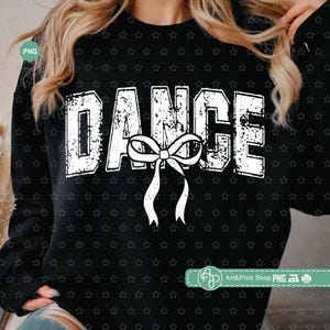 May include: Black sweatshirt with the word "DANCE" in distressed white lettering. A white bow with flowing ribbons is centered below the word. The background is covered in small white stars.