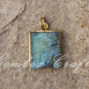 Pode incluir: Um pingente de ouro com uma pedra retangular de labradorita azul. O pingente tem um design simples e é perfeito para adicionar um toque de elegância a qualquer roupa.