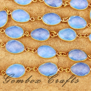 May include: A strand of light blue oval-shaped gemstone beads connected by a gold chain. The beads have a faceted design and a translucent appearance.