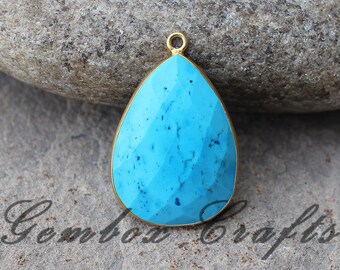 Op de afbeelding: Een traanvormige turquoise hanger met een gouden bail. De edelsteen heeft een lichtblauwe kleur en een gladde, gepolijste afwerking.