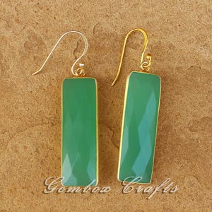 May include: A pair of rectangular green earrings with a faceted surface and gold-coloured trim. The earrings have a hook closure. The image also includes the text "Gembow Crafts".