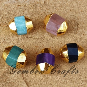May include: Five gemstone beads with gold accents. The beads are in shades of blue, green, pink, purple, and black.