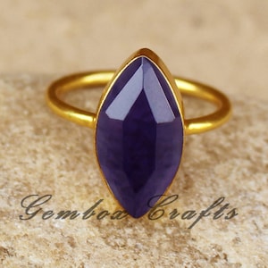 May include: A gold ring with a large, faceted, purple gemstone in a marquise shape.