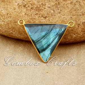 Può includere: Ciondolo triangolare placcato oro con una pietra preziosa in labradorite blu. Il ciondolo ha due anelli a salto per attaccarlo a una catena o un cordino.