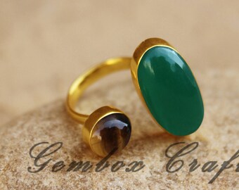 May include: Gold ring with a green oval gemstone and a smaller brown oval gemstone. The ring is open and adjustable.