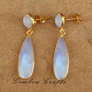 May include: A pair of gold dangle earrings with iridescent moonstone teardrop-shaped stones. The earrings have a simple post back.