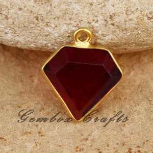 May include: Gold-toned pendant featuring a red faceted gemstone in the shape of a diamond.