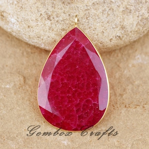 May include: A teardrop-shaped pendant made of red agate with a gold-toned metal bail. The agate has a textured, marbled appearance.