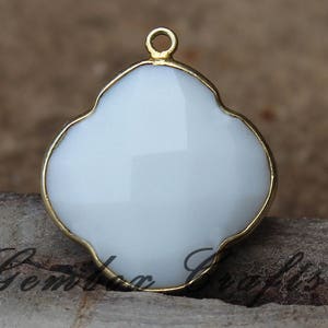 May include: Gold-tone pendant with a white, four-leaf clover shaped cabochon.