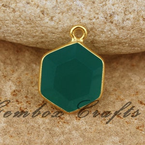 May include: Gold-toned pendant with a green gemstone in a hexagonal shape.