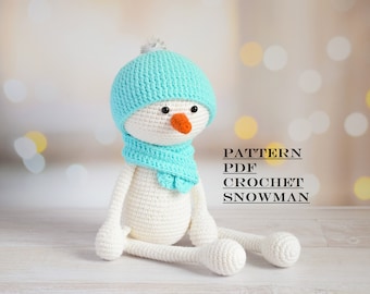 May include: Crochet pattern PDF for a white snowman wearing a light blue hat and scarf. PATTERN PDF CROCHET SNOWMAN
