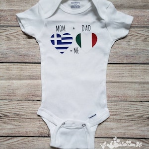 May include: White baby onesie with the text "MOM + DAD = ME" in black. The plus sign is replaced with a heart containing the Greek flag and the equals sign is replaced with a heart containing the Italian flag.
