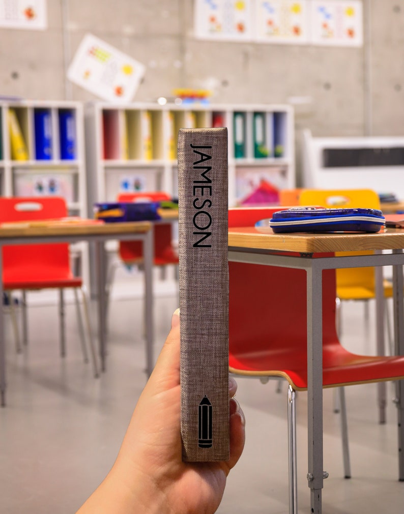 K&ouml;nnte beinhalten: Ein graues Buch mit dem Wort "JAMESON" vertikal auf dem R&uuml;cken gedruckt. Ein Bleistift-Symbol ist unten auf dem R&uuml;cken gedruckt.
