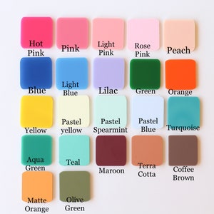 May include: A collection of square acrylic color swatches in various shades, including pink, blue, green, and orange. Each swatch is labeled with its color name, such as "Hot Pink," "Blue," and "Olive Green." The swatches are arranged on a white surface.