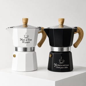 May include: Two moka pots, one white and one black, featuring wood-look handles and knobs. The white pot is engraved with a coffee cup icon and the text "Matt & Tina 20 years". The black pot features a coffee cup icon and the text "You bean so much to me I love you a latte".