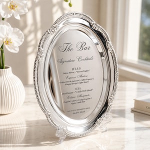 May include: A silver oval bar sign with ornate detailing, displaying "The Bar" and "Signature Cocktails." The sign lists cocktail recipes, including "Dolce Notte" and "Classic Margarita." The date "06.06.2026" is also visible.