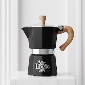 May include: A black moka pot coffee maker with a light wood-grain handle and lid knob. The base features the white printed text Mr. Logic with a crown icon above the M and the number 007 with a spade symbol below the text on the front side.