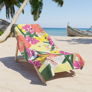 May include: A beach chair with a floral patterned towel. The towel features pink, yellow, and orange flowers on a white background.